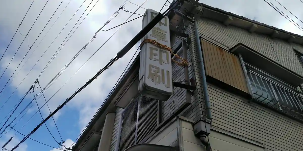 台風等の災害による看板修理：強風で落下しかけている看板